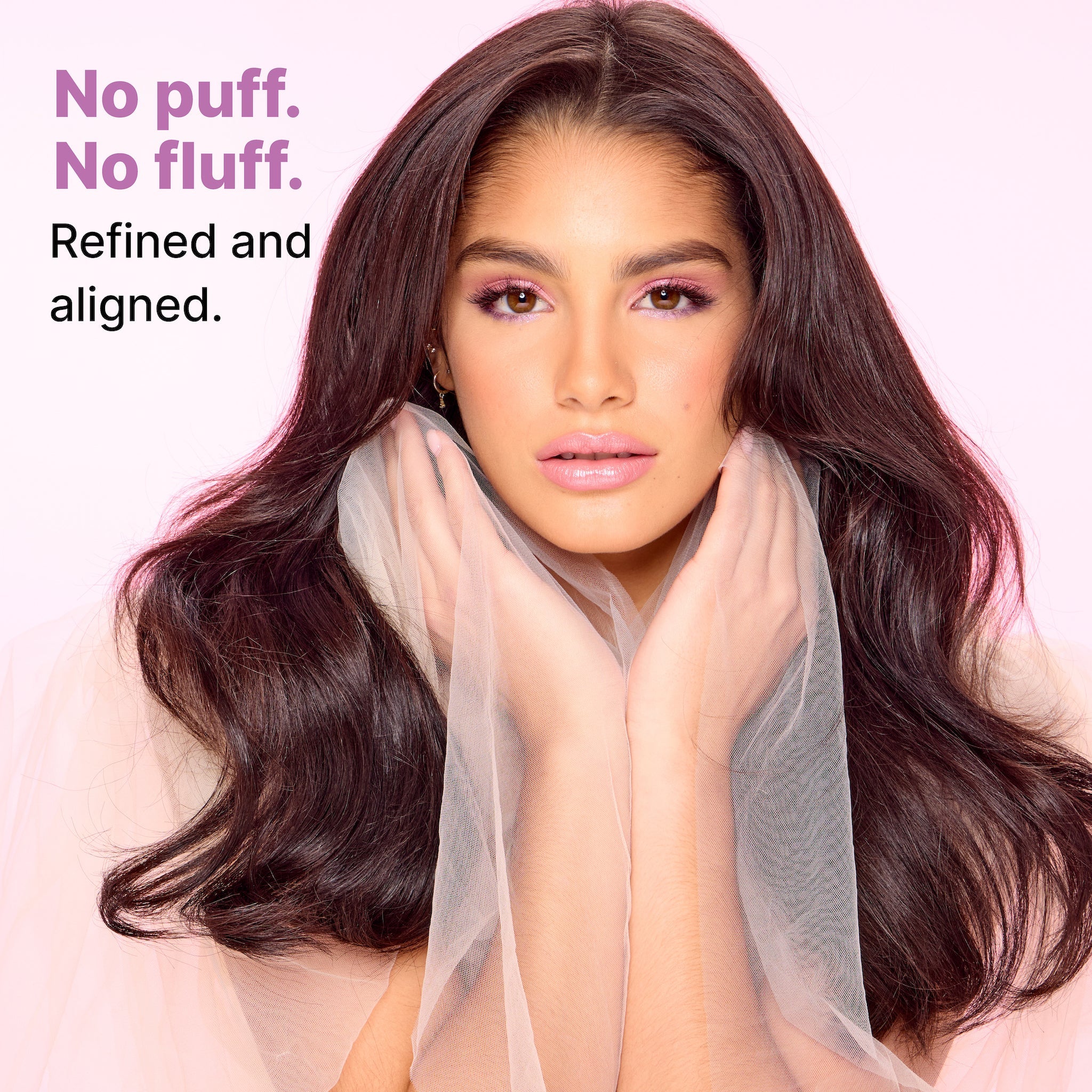A woman with long, sleek, shiny hair styled in soft waves, wearing a sheer, flowing pink scarf around her neck. Text on the left reads “No puff. No fluff. Refined and aligned.” highlighting the transformation to smooth, refined hair with a polished finish.